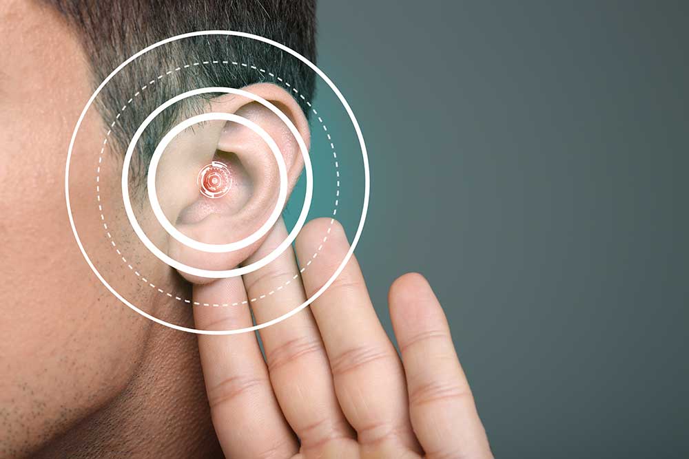 A person holds their hand behind their ear, with digital concentric circles overlayed, symbolizing hearing or listening closely, on a gray background.